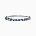 The Nahla Siri 14K White Gold Tanzanite Diamond Bangle, 4.76 TCW, features a row of blue triangle-cut tanzanite gems set between small diamonds along the top half of the band.