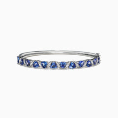 The Nahla Siri 14K White Gold Tanzanite Diamond Bangle, 4.76 TCW, features a row of blue triangle-cut tanzanite gems set between small diamonds along the top half of the band.