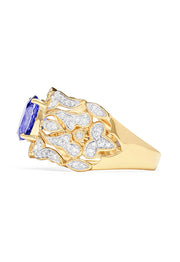 The 14K Yellow Gold Tanzanite and Diamond Ring, 1.45 TCW, showcases a large oval tanzanite center with shimmering white diamonds along the intricately designed openwork band.