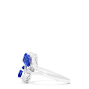 The 14K White Gold Pear Shaped Tanzanite and Diamond Bypass Ring, 0.74 TCW, features two pear-shaped blue tanzanites each with a diamond halo, set side by side in an elegant bypass design.