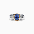 This Mens 14K Two-Tone Gold Tanzanite Diamond Ring, 1.90 TCW, features an oval blue tanzanite in a gold bezel on a silver band, accented by rows of sparkling round diamonds on each side.