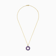 A 14K yellow gold necklace with a thin chain and a circular pendant featuring amethyst, tanzanite, and diamond gemstones, displayed on a white background.