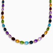 The Mosaic 14K Yellow Gold Multi Gemstone Necklace showcases oval-shaped, multicolored gemstones evenly spaced along a gold chain, shown against a white background.