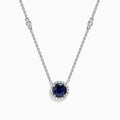 The Royale Bleu 14K White Gold Sapphire and Diamond Necklace, 1.11 TCW, features a round blue sapphire pendant with a halo of clear stones and two diamonds set along each side of the chain.
