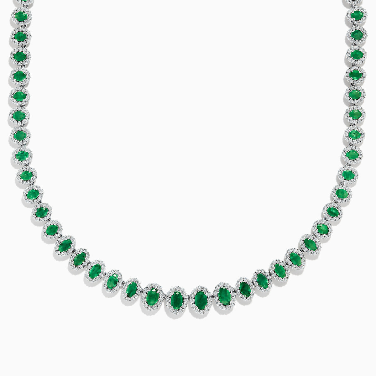 The 14K White Gold Emerald and Diamond Tennis Necklace showcases oval green emeralds, each surrounded by sparkling diamonds, evenly set along a white gold chain displayed on a white background.