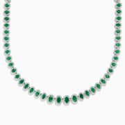 The 14K White Gold Emerald and Diamond Tennis Necklace showcases oval green emeralds, each surrounded by sparkling diamonds, evenly set along a white gold chain displayed on a white background.