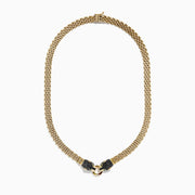 The Signature 14K Gold Black Diamond and Emerald Panther Necklace, 1.27 showcases two black panther heads with emerald eyes facing each other and holding a gold ring at the center in a textured design.