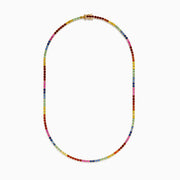 The Watercolors 14K Yellow Gold Multi Sapphire Tennis Necklace features small, round sapphires in a rainbow pattern, elegantly set in yellow gold and arranged in a smooth curve.