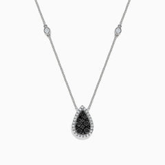 The 14K White Gold Black and White Diamond Pear Shaped Necklace, 1.09 TCW, features a teardrop pendant with black and white diamonds at the center, haloed by clear stones, plus two small clear stones set along the chain.