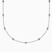 The 14K White Gold Diamond and Tanzanite Stationary Necklace showcases alternating round tanzanite and diamond gems set along a fine chain, displayed against a white background.
