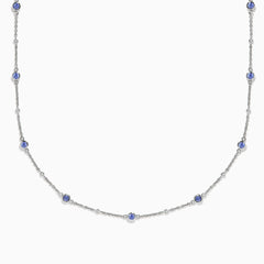 The 14K White Gold Diamond and Tanzanite Stationary Necklace showcases alternating round tanzanite and diamond gems set along a fine chain, displayed against a white background.
