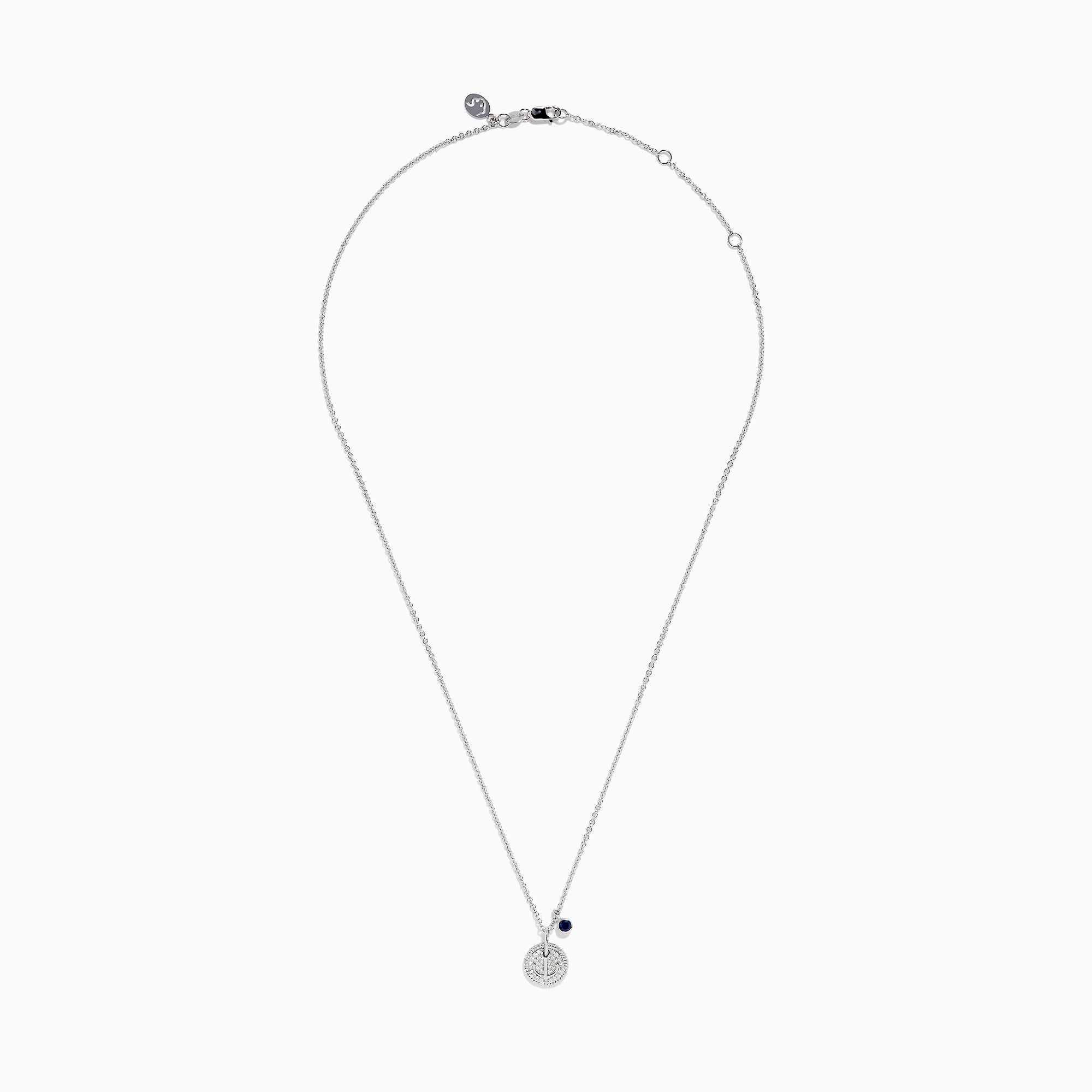 The Seaside Sterling Silver Sapphire and Diamond Anchor Necklace features a round, crystal-studded anchor pendant with a small dark blue sapphire charm, elegantly displayed on a white background.