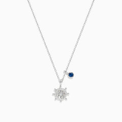 The Seaside Sterling Silver Diamond and Sapphire Ship Wheel Pendant features a ship wheel design with diamond accents and a sapphire charm, showcased on a sterling silver chain against a white background.