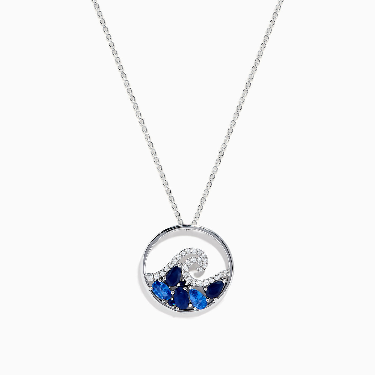 The Seaside 14K White Gold Blue Sapphire and Diamond Wave Pendant is a silver necklace featuring a circular pendant with blue sapphires and diamonds, reflecting the beauty of ocean waves and foam.