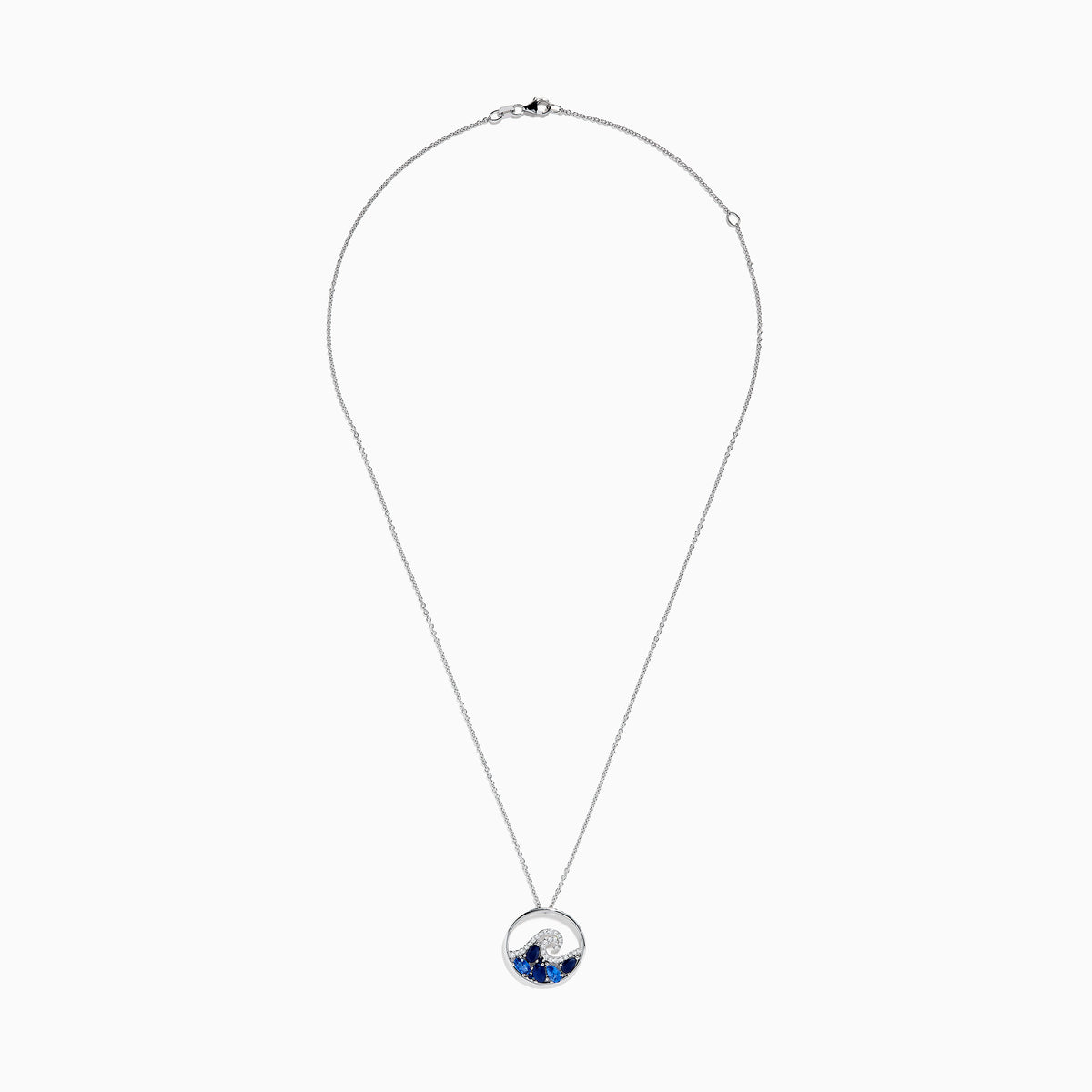 The Seaside 14K White Gold Blue Sapphire and Diamond Wave Pendant is a silver necklace featuring a circular pendant with blue sapphires and diamonds, reflecting the beauty of ocean waves and foam.