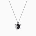 Introducing the Seaside Sterling Silver Black and White Diamond Turtle Pendant, 0.32 TCW—a stunning necklace featuring a turtle-shaped charm adorned with sparkling black and white diamond accents. A delicate silver baby turtle charm gracefully hangs from its side, adding a unique touch to this elegant design.