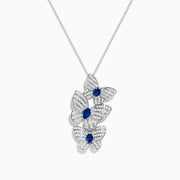 The 14K White Gold Blue Sapphire and Diamond Multi Butterfly Pendant features three butterflies accented with diamond-like stones and a central blue sapphire, hanging elegantly from a delicate chain.