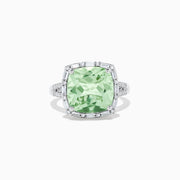 The 14K White Gold Green Amethyst and Diamond Ring showcases a cushion-cut green amethyst center, accented by a halo of clear baguette and round diamonds, all set in white gold.
