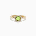 The 14k Yellow Gold Peridot and Diamond Ring, 1.10 TCW, showcases a round green peridot center encircled by a halo of sparkling diamonds, all set in yellow gold and displayed against a white background.