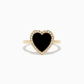 The 14K Yellow Gold Onyx and Diamond Heart Ring features a large heart-shaped onyx surrounded by sparkling diamonds, all set in yellow gold. Shown against a plain white background.