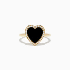 The 14K Yellow Gold Onyx and Diamond Heart Ring features a large heart-shaped onyx surrounded by sparkling diamonds, all set in yellow gold. Shown against a plain white background.