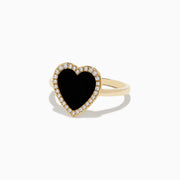 The 14K Yellow Gold Onyx and Diamond Heart Ring features a large heart-shaped onyx surrounded by sparkling diamonds, all set in yellow gold. Shown against a plain white background.