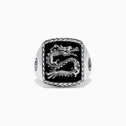 The Mens 925 Sterling Silver Onyx Dragon Ring, 5.00 TCWS, features a rectangular black onyx face with a raised dragon design, a textured border, and circular patterns on the sides.