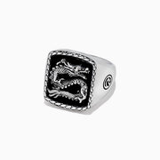 The Mens 925 Sterling Silver Onyx Dragon Ring, 5.00 TCWS, features a rectangular black onyx face with a raised dragon design, a textured border, and circular patterns on the sides.