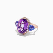 The 14K Rose Gold Amethyst, Tanzanite and Diamond Ring, 10.28 TCW features a striking amethyst center, accented by tanzanites and surrounded by a sparkling diamond halo.