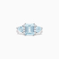 The Aquarius 14K White Gold Aquamarine and Diamond Ring, 3.30 TCW, showcases a large emerald-cut aquamarine center stone with two triangular blue side stones and sparkling round diamonds for added brilliance.