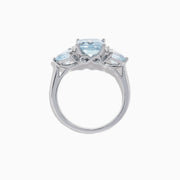 The Aquarius 14K White Gold Aquamarine and Diamond Ring, 3.30 TCW, showcases a large emerald-cut aquamarine center stone with two triangular blue side stones and sparkling round diamonds for added brilliance.