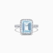 The Aquarius 14K White Gold Aquamarine and Diamond Ring, 3.33 TCW, features a large emerald-cut aquamarine surrounded by a diamond halo and set on a diamond-studded band, shown on a white background.