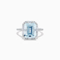 The Aquarius 14K White Gold Aquamarine and Diamond Ring showcases a large emerald-cut aquamarine center stone encircled by sparkling diamonds, presented against a white background.