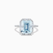 The Aquarius 14K White Gold Aquamarine and Diamond Ring showcases a large emerald-cut aquamarine center stone encircled by sparkling diamonds, presented against a white background.