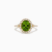 The 14K Yellow Gold Peridot and Diamond Ring showcases an oval-cut green peridot center, encircled by a halo of round white diamonds, with extra diamonds set along the band.