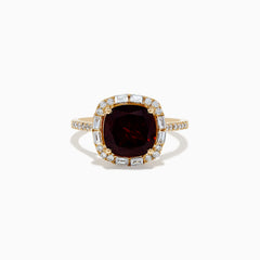 The 14K Yellow Gold Garnet and Diamond Ring features a cushion-cut deep red garnet center, surrounded by a halo of baguette and round white diamonds, with more diamonds set along the band.
