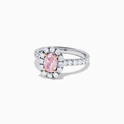 A GIA certified faint pink diamond ring, 1.53 TCW, set in a halo of round white diamonds on an 18K two tone gold band. Shown on a plain white background.