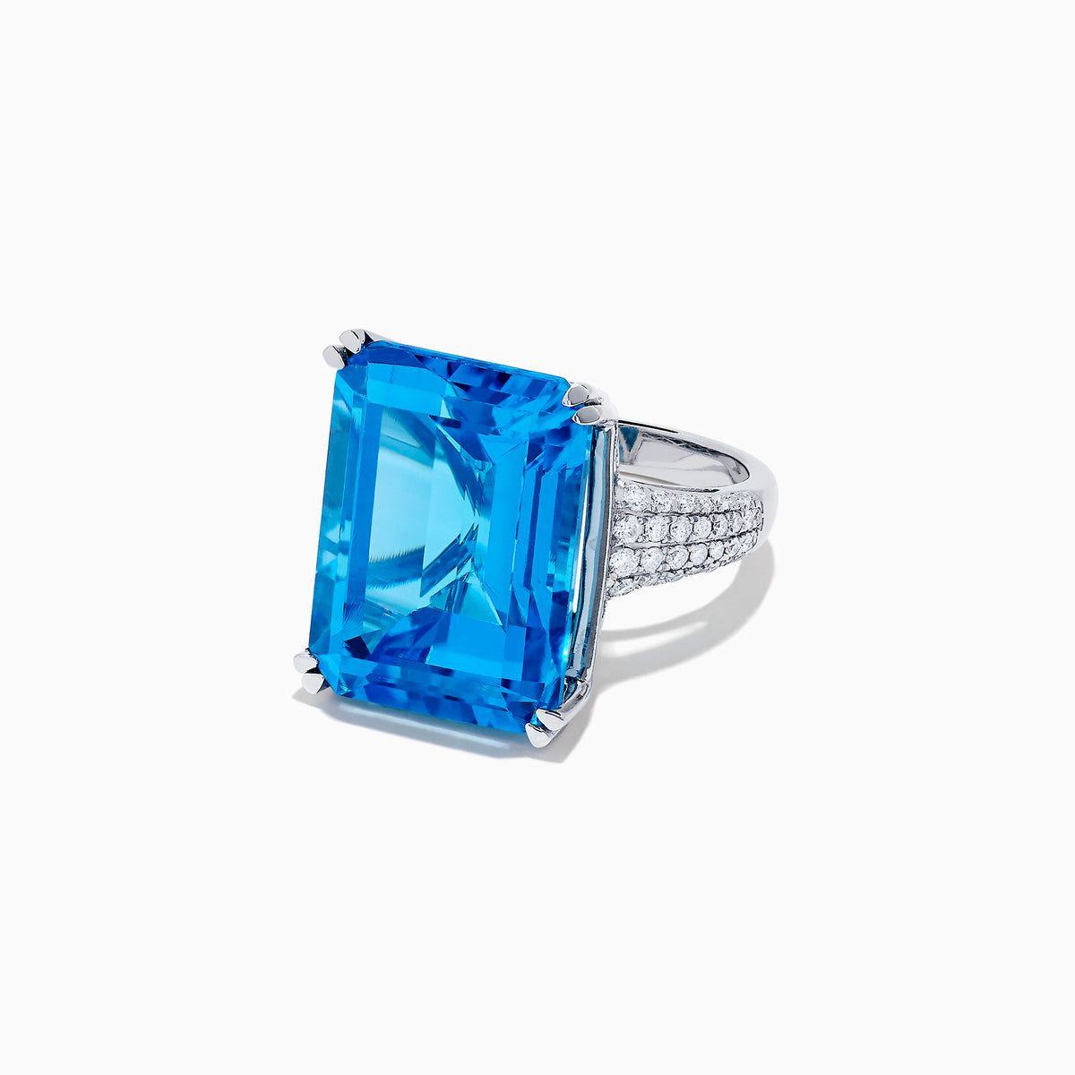 The 14K White Gold Blue Topaz and Diamond Ring, 29.29 TCW, features a large rectangular emerald-cut blue topaz accented by small white diamonds, shown on a white background.