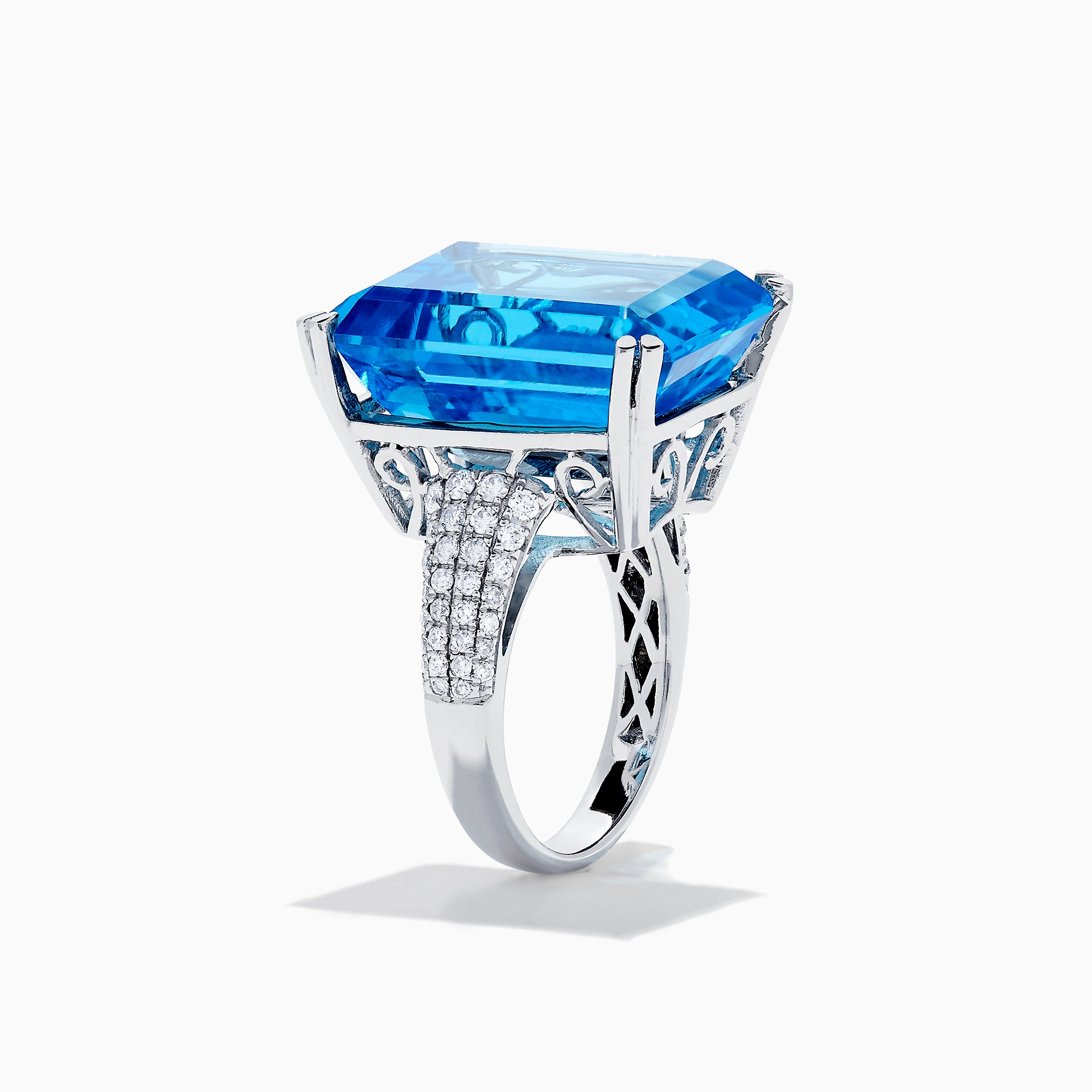 The 14K White Gold Blue Topaz and Diamond Ring, 29.29 TCW, features a large rectangular emerald-cut blue topaz accented by small white diamonds, shown on a white background.