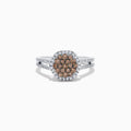 This 14K White Gold Espresso and White Diamond Ring features a split shank and a 1.50 TCW cluster of round brown diamonds at the center, surrounded by a halo of sparkling white diamonds.