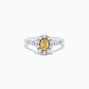 The 14K White Gold White and Fancy Yellow Diamond Ring, 1.10 TCW, features an oval yellow diamond center, haloed by clear round diamonds with more diamonds along the band—a timelessly elegant piece.