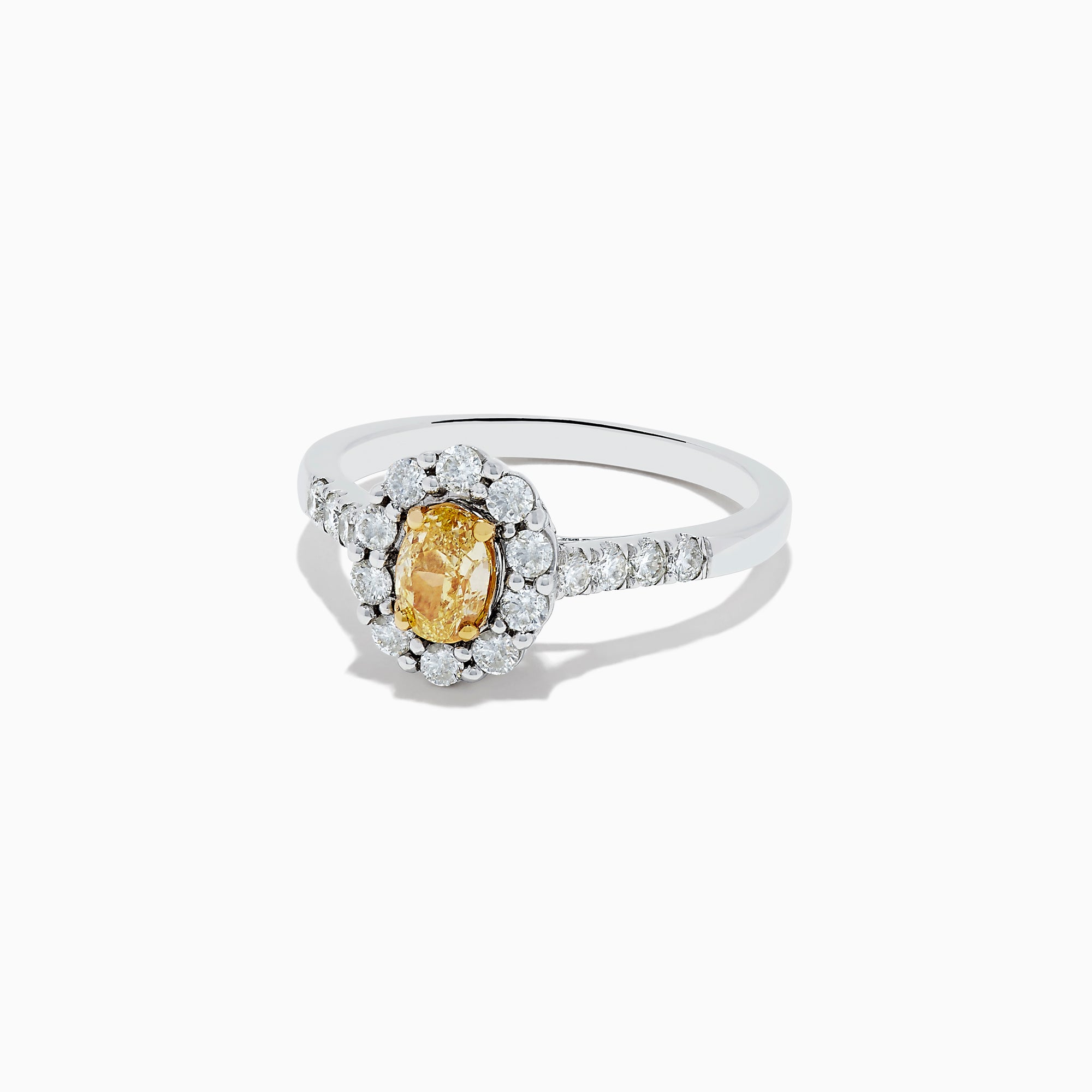 The 14K White Gold White and Fancy Yellow Diamond Ring, 1.10 TCW, features an oval yellow diamond center, haloed by clear round diamonds with more diamonds along the band—a timelessly elegant piece.