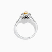 The 14K White Gold White and Fancy Yellow Diamond Ring, 1.10 TCW, features an oval yellow diamond center, haloed by clear round diamonds with more diamonds along the band—a timelessly elegant piece.