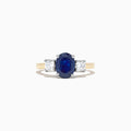 The Royale Bleu 14K Two Tone Gold Sapphire and Diamond Ring, 2.39 TCW, features an oval blue sapphire between two oval white diamonds, set in luxurious gold and shown on a white background.