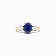 The Royale Bleu 14K Two Tone Gold Sapphire and Diamond Ring, 2.39 TCW, features an oval blue sapphire between two oval white diamonds, set in luxurious gold and shown on a white background.