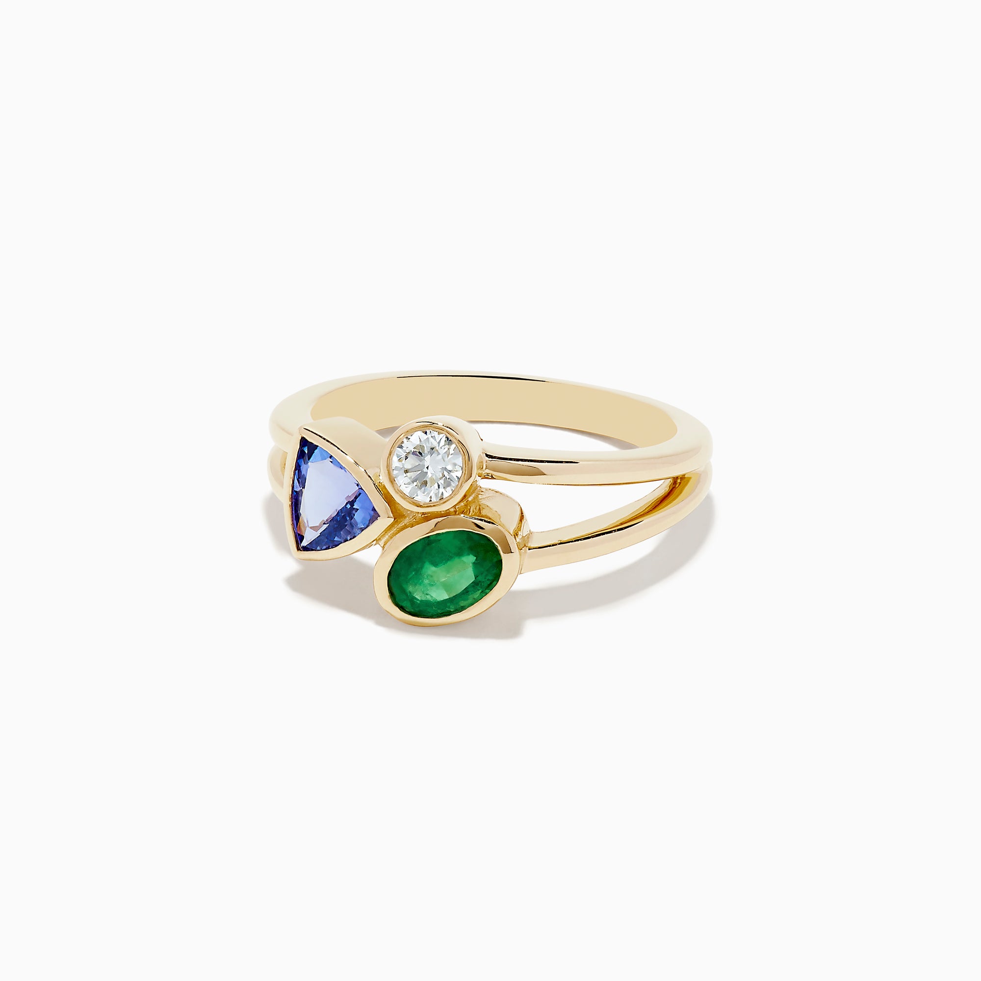 The 14K Yellow Gold Tri Stone Diamond, Emerald, and Tanzanite Ring features a split band with a round diamond, triangular tanzanite, and oval emerald arranged in an asymmetrical cluster.