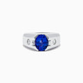 Mens 14K white gold ring featuring a large oval blue tanzanite center stone, accented by two small round diamonds on each side, set against a white background.