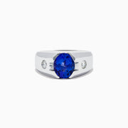 Mens 14K white gold ring featuring a large oval blue tanzanite center stone, accented by two small round diamonds on each side, set against a white background.