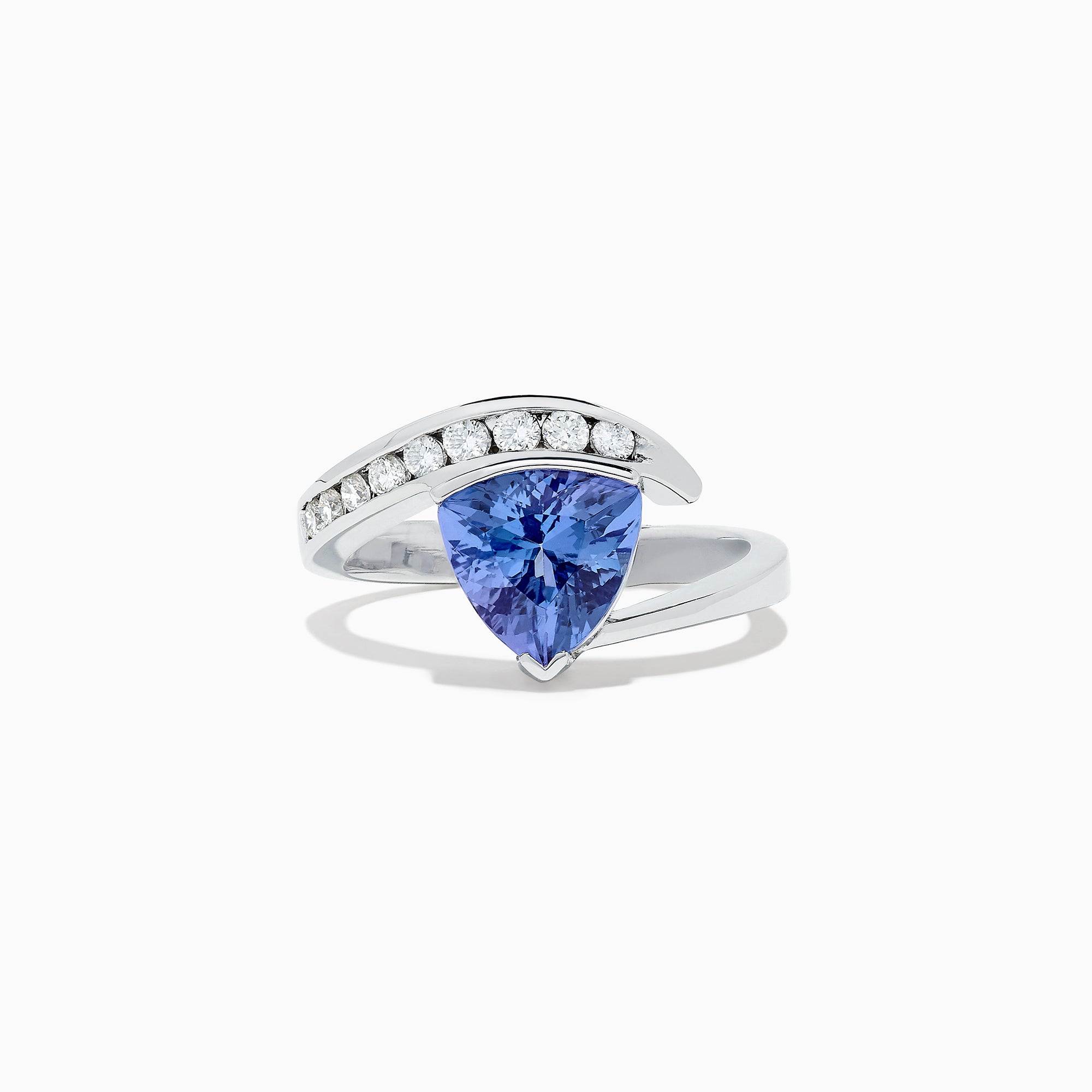 The Nahla Siri 14K White Gold Tanzanite and Diamond Ring, 1.88 TCW, showcases a large triangular blue tanzanite center with a curved band of round diamonds above it, set in an elegant modern design.
