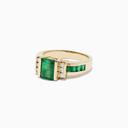 The Brasilica 14K Yellow Gold Emerald and Diamond Ring, 2.26 TCW, showcases a large rectangular emerald center with three round diamonds on each side and extra green stones set along the band for added elegance.